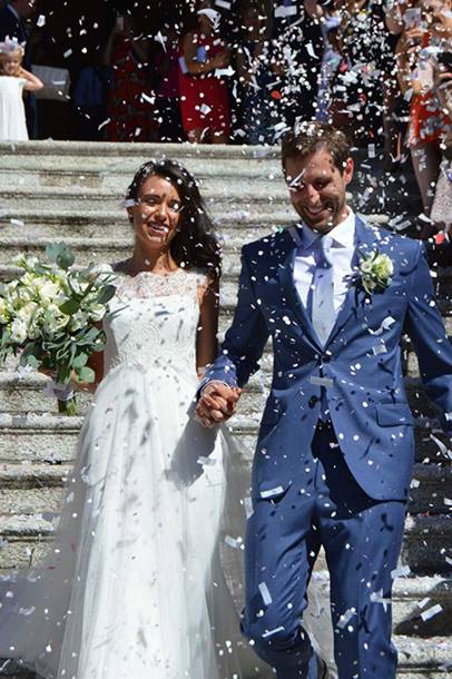 Fran, wearing the wedding dress she donated to a British Red Cross charity shop, stands holding her new husband's hand while confetti is thrown at them.
