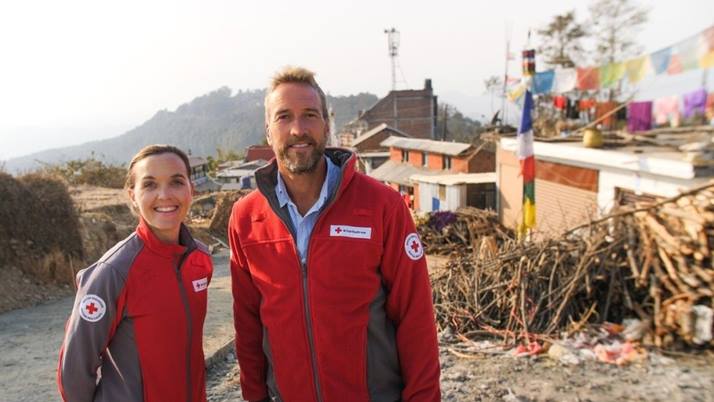 Ben Fogle and Victoria Pendleton smiling at the camera in their British Red Cross uniform.