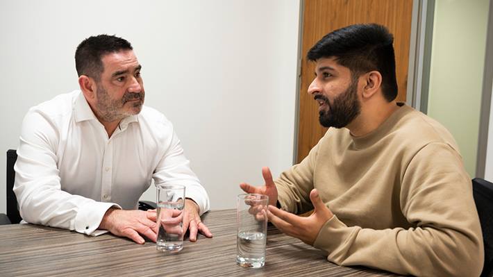 Two people in discussion at table within an office environment.