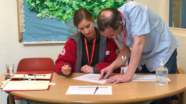 Volunteers from the family tracing and reunion service sit at a table and look through some paperwork.