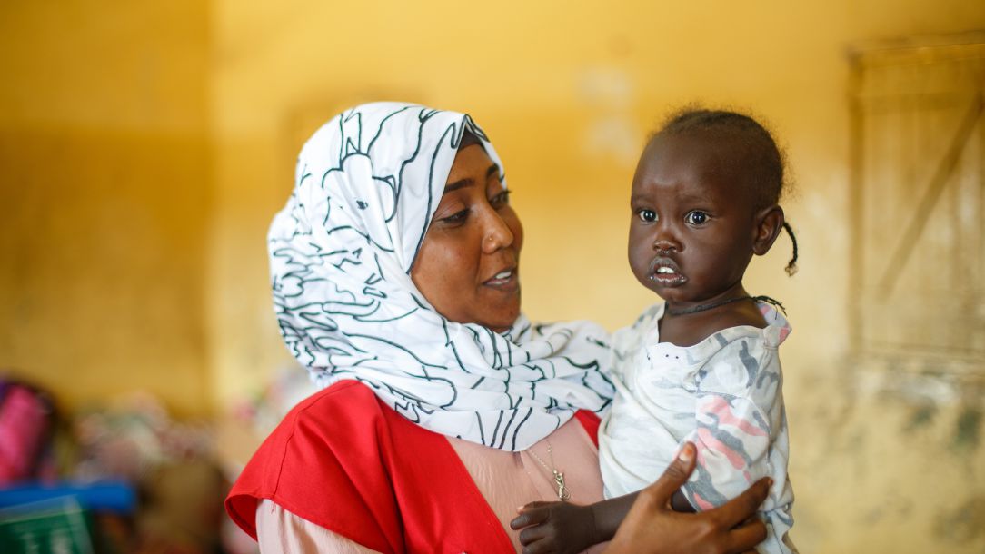 A Sudanese Red Cross nurse in Port Sudan with a young child who fled conflict.