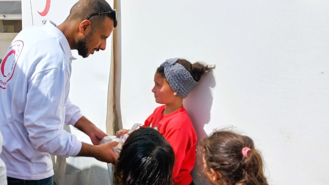 A Palestine Red Crescent volunteer delivers aid to children in Gaza