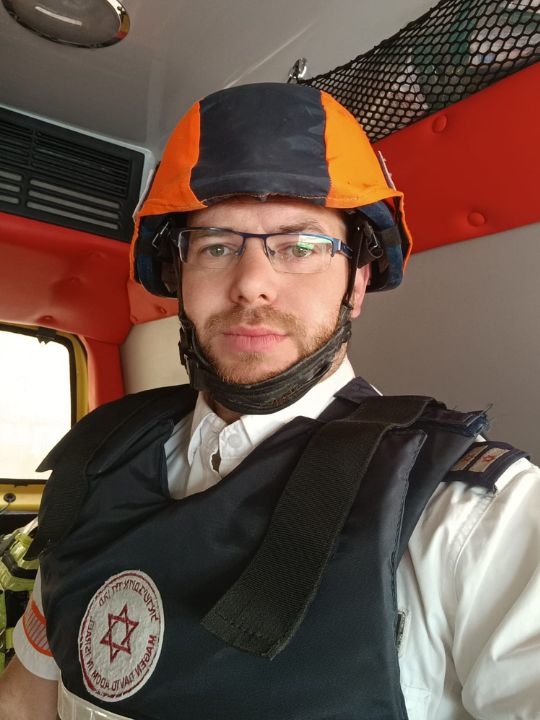 MDA ambulance driver Haim sits in his ambulance in uniform, looking at the camera.