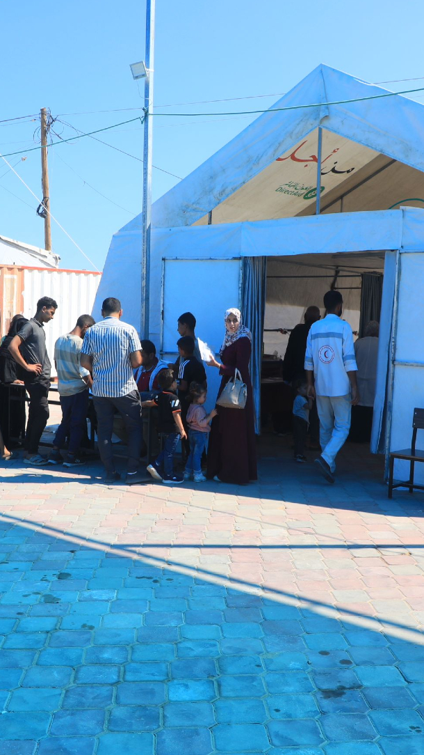 A queue waiting outside the entrance of a large tent, part of al-Mawasi field hospital.