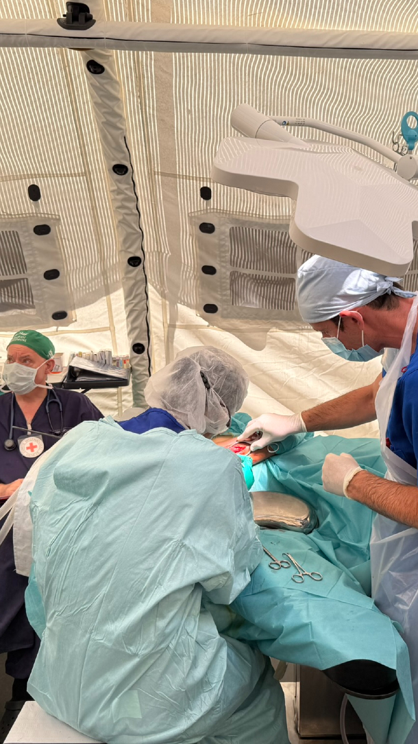 Two surgeons carry out emergency surgery on a patient.