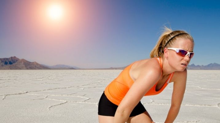 An exhausted woman bends down after exercising, as the sun beats down as part of a British Red Cross blog on beating the heat.