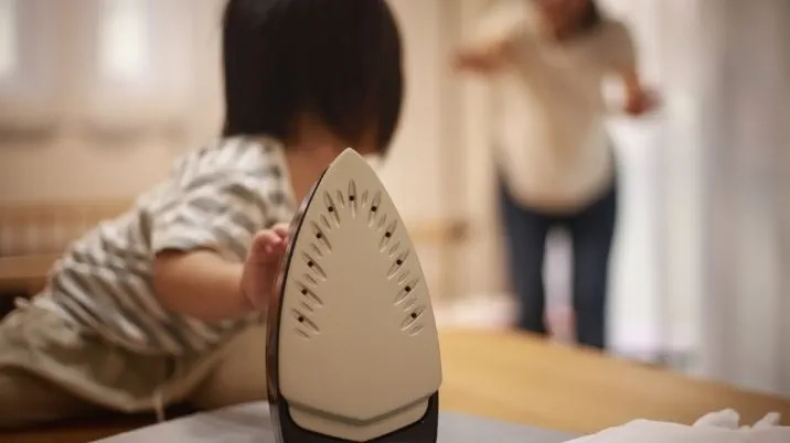 A small child reaches for a hot iron.