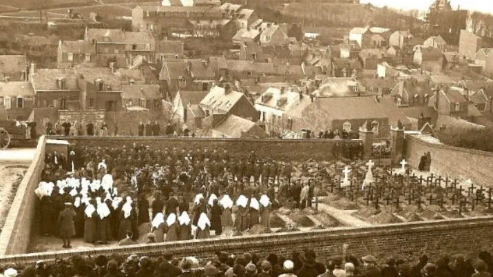 A black and white photograph showing crowds of people and groups of British Red Cross nurses at the funeral of nurse (VAD), Peggy Arnold.