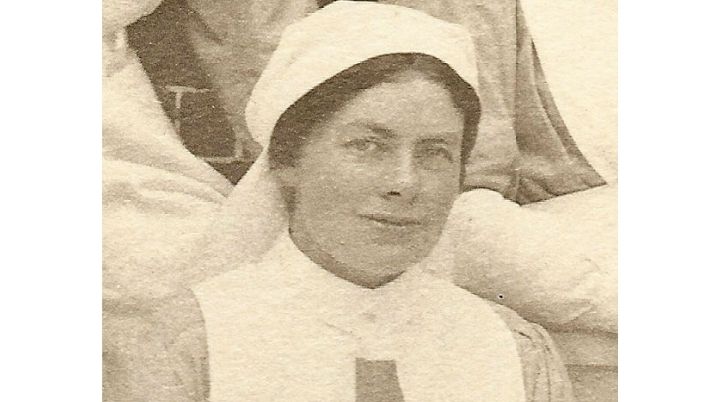 Black and white photograph of British Red Cross nurse Peggy Arnold, dressed in her nurses uniform and smiling at the camera.