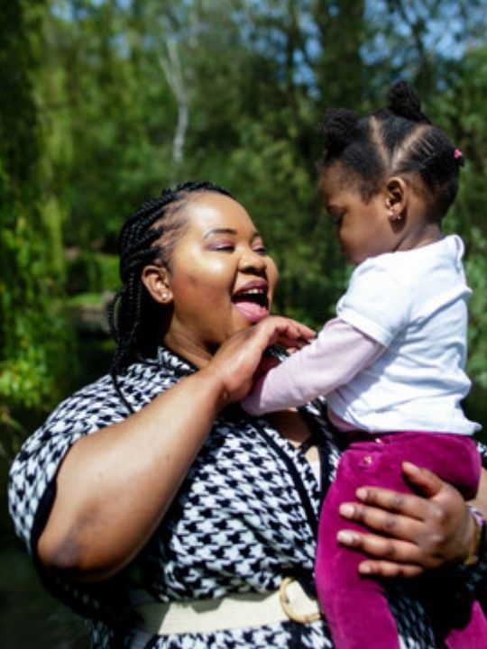 Alvina, part of the VOICES network, holds her baby up and laughs.