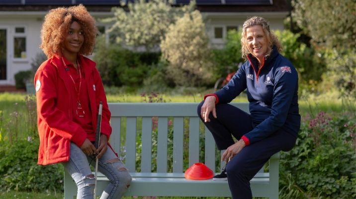 Olympic gold medallist Sally Gunnell sits on a bench with British Red Cross volunteer, Abi.