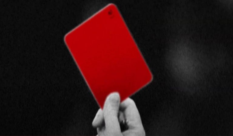 A referee holds up a red card.