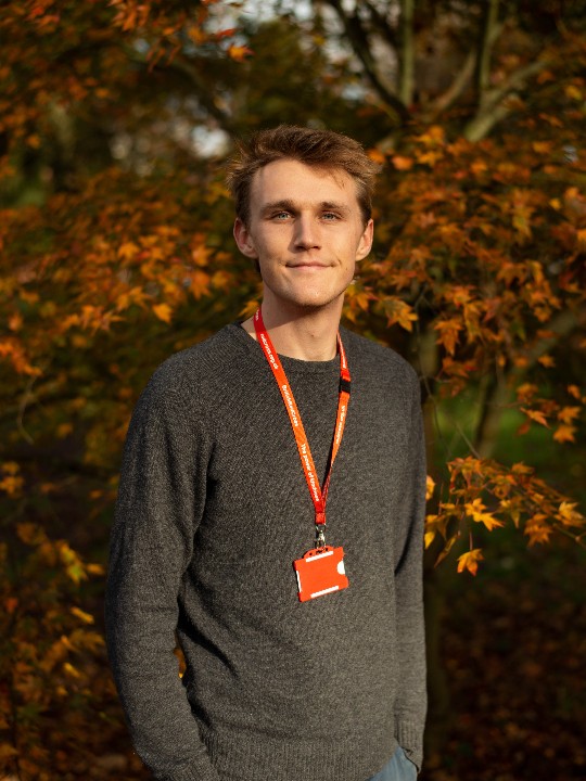 Volunteer Tom smiles at the camera, wearing his British Red Cross identity badge