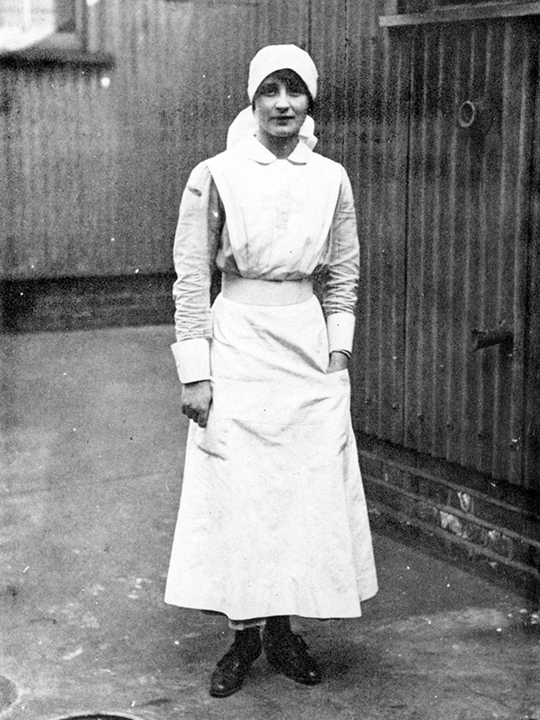 Vera Brittain stands wearing her Red Cross nurse's uniform.