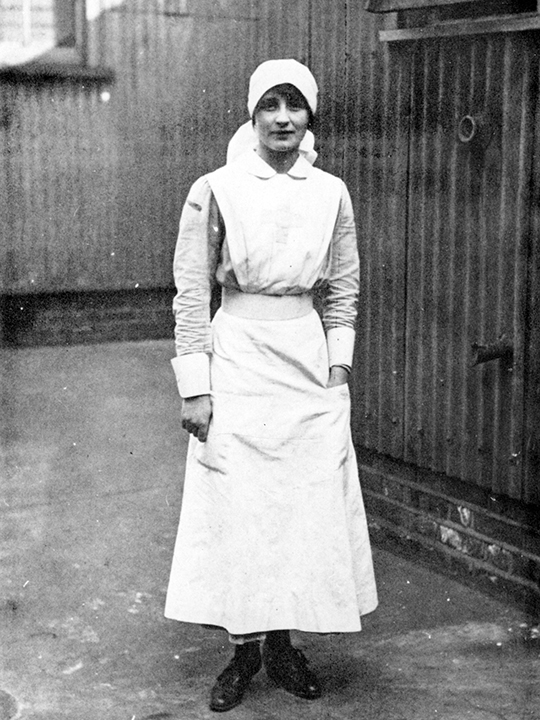 Vera Brittain stands wearing her Red Cross nurse's uniform.
