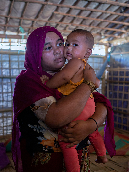 Mother-of-three Amina Khatun holds one of her children. She is a member of the widow’s block.