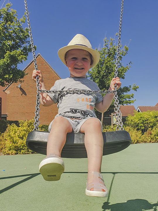 Two-year-old William smiling while on a swing