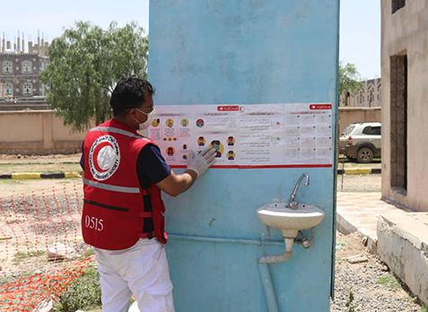 Member of the Yemen Red Crescent puts up a hygiene education poster.