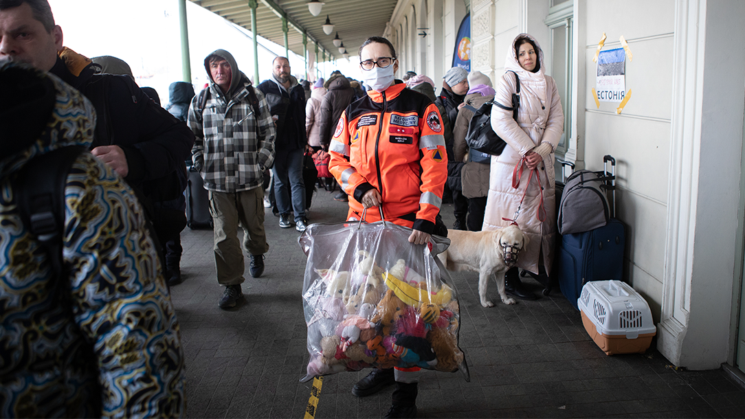 Magdelana, a Polish Red Cross volunteer, stands in a train station holding a plastic bag full of stuffed toys. 