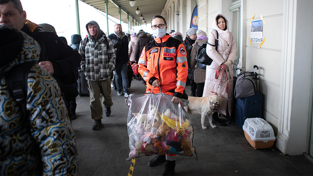 Magdelana, a Polish Red Cross volunteer, stands in a train station holding a plastic bag full of stuffed toys.