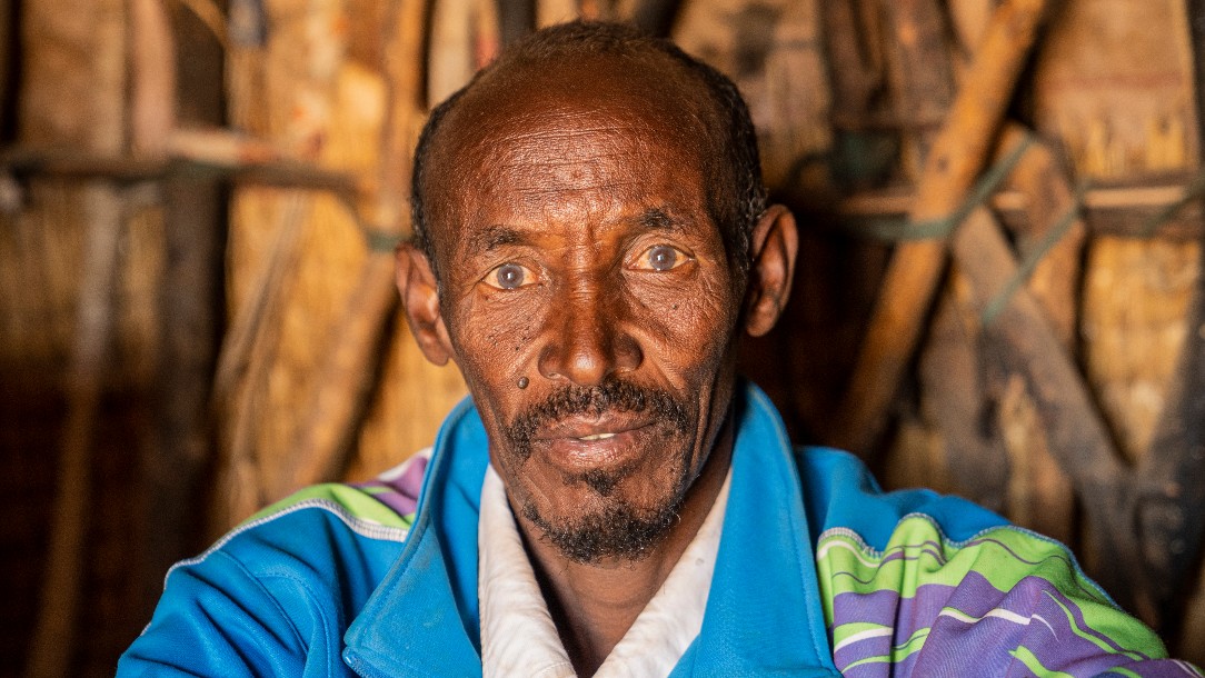 A man wearing a blue jacket looks straight at the camera