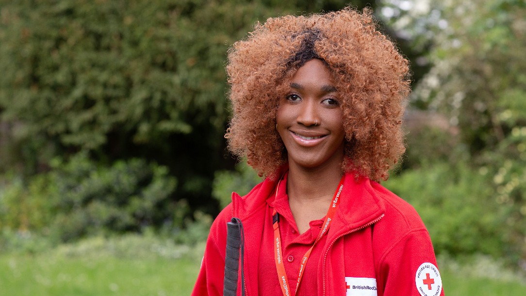 A volunteer named Abi smiles at the camera, wearing her Red Cross uniform