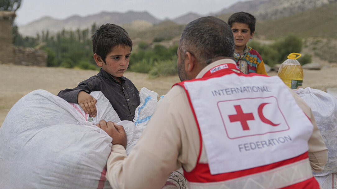 A worker from the Red Cross/Red Crescent gives food aid to children after the earthquake in Afghanistan.