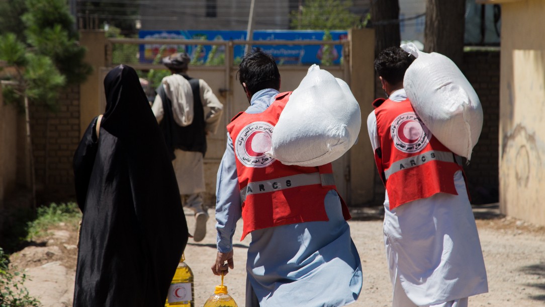 Afghan Red Crescent Society volunteers help disabled people carry their food packages home from the relief distribution point, in this photograph taken in July 2020