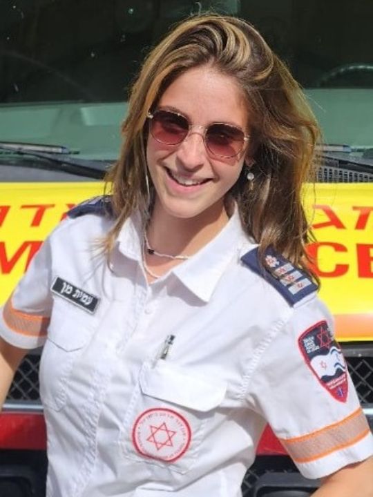 Amit Mann, a responder from MDA, stands smiling in front of her ambulance.