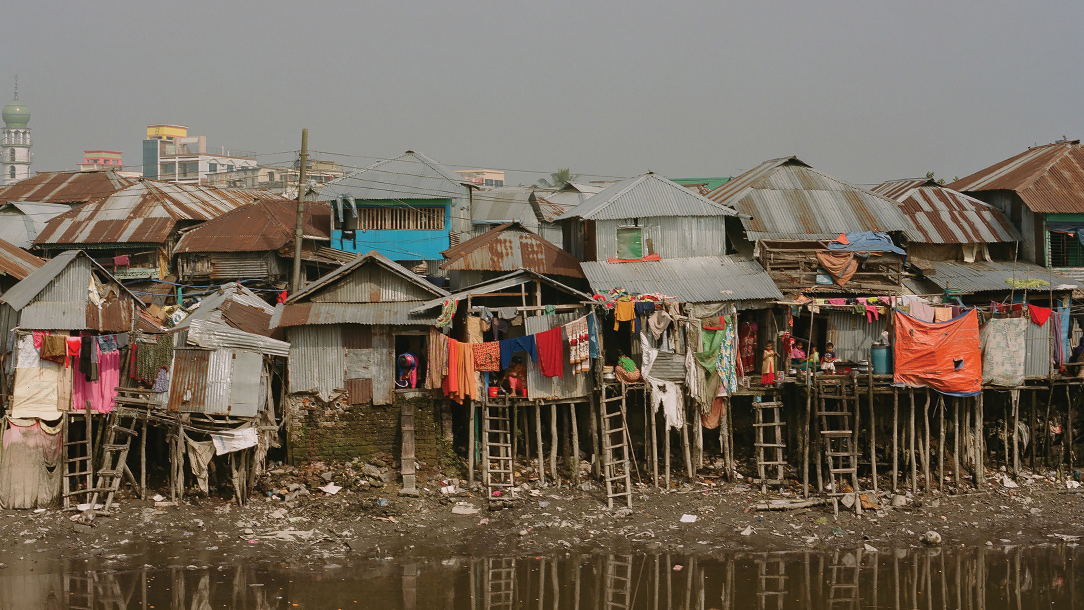 Houses built on thin poles to hold them up in case of floods line a river bank in Barishal, Bangladesh.