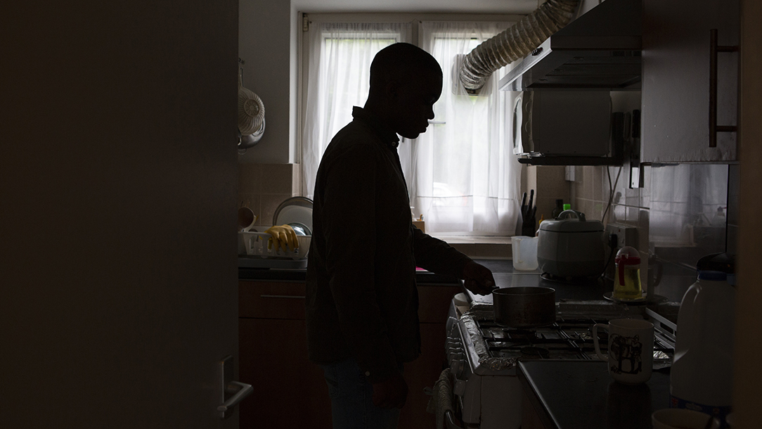 A man standing in a kitchen in a silhouette.