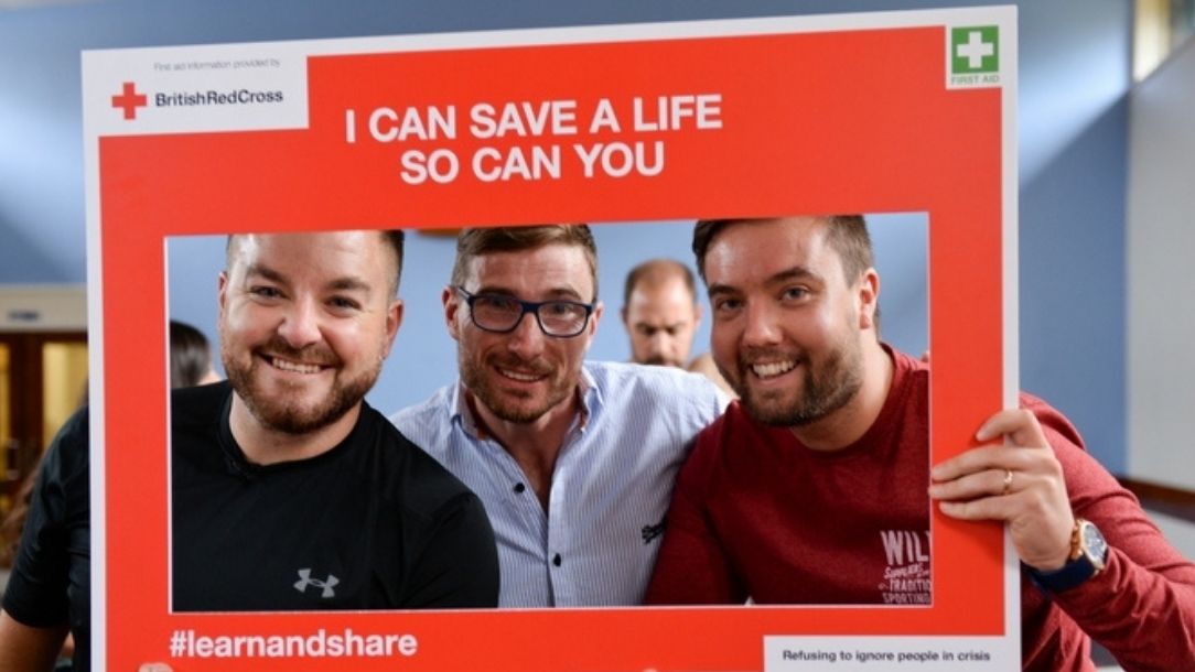 Presenter Alex Brooker and two of his friends attend a British Red Cross first aid course and hold up a sign saying "I can save a life, so can you".