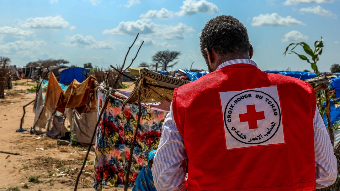 Ahmat, a Chad Red Cross volunteer enters the improvised camp on the site of Adré High School in Chad. Makeshift shelters are seen in the background