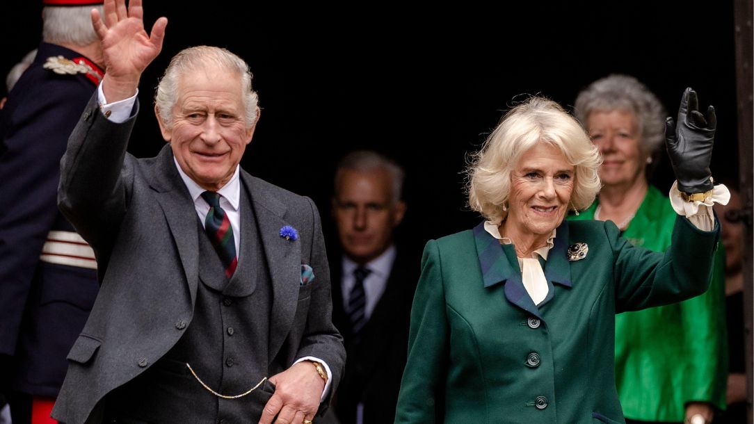 King Charles and Queen Consort Camilla waving at some crowds.