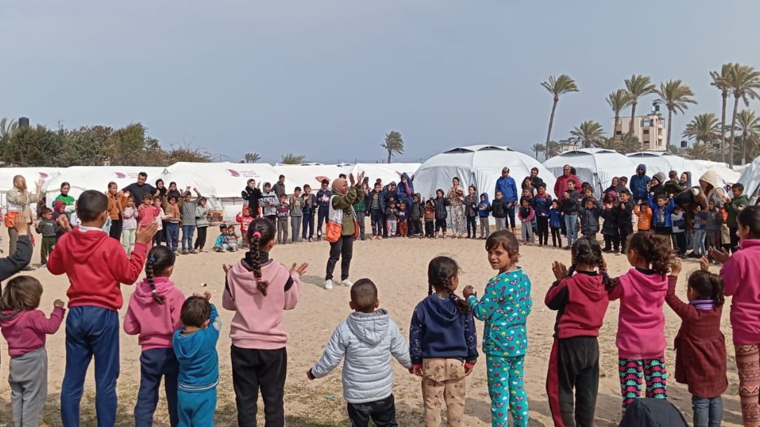 Children sing songs in a circle as Palestine Red Crescent staff try to entertain them in Gaza.