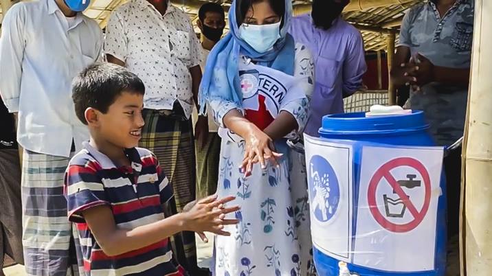 Young boy and a woman in Bangladesh following hand hygiene instructions.