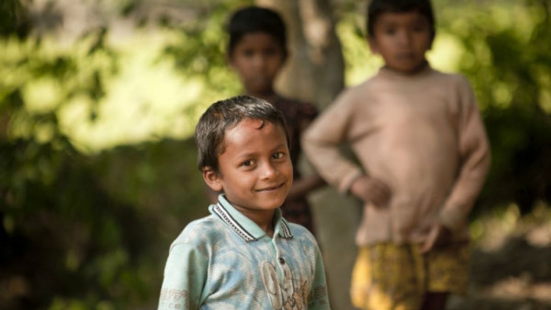Three young boys in Bangladesh smile at the camera.