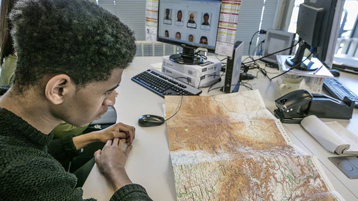 Man sits at desk and looks at a map