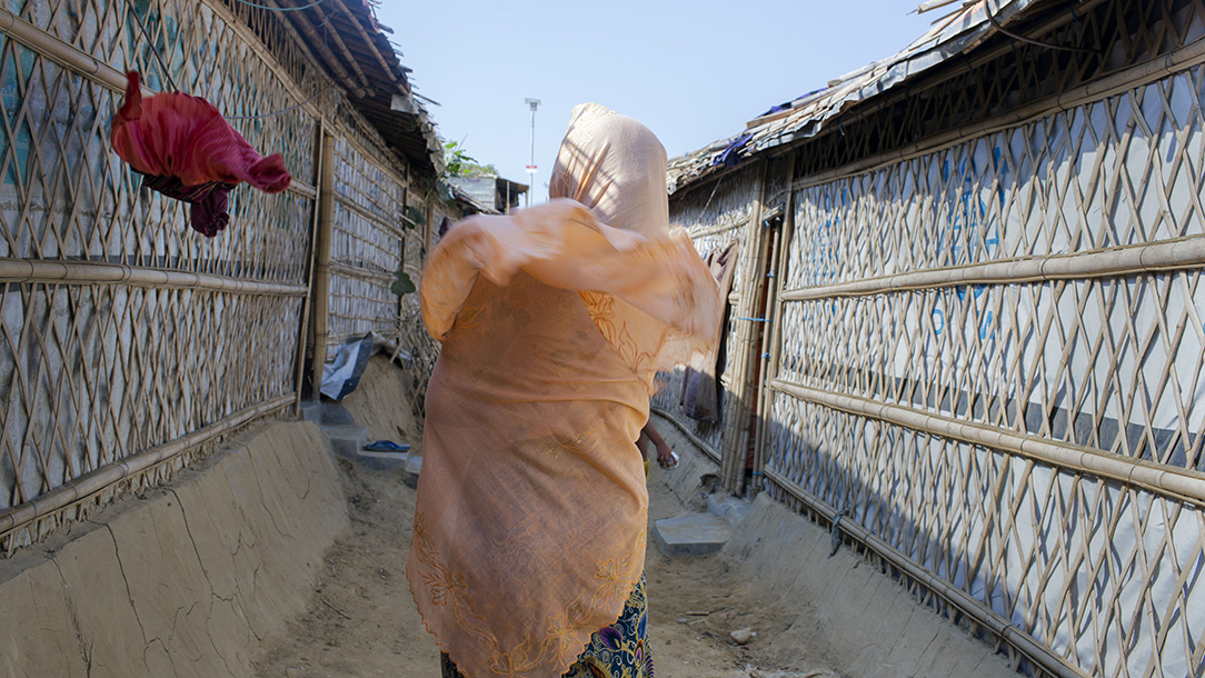 Woman walks down a narrow path during windy weather