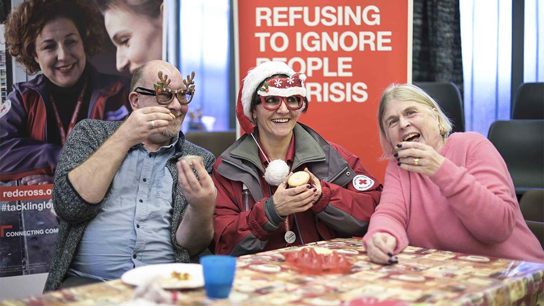 Three people eating cake at a festive party for volunteers and service users.