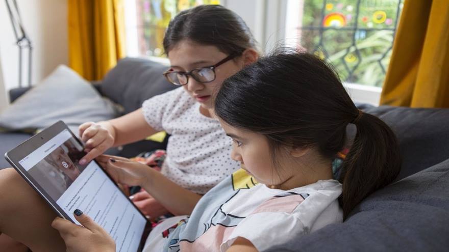Two sisters learning first aid at home on a tablet