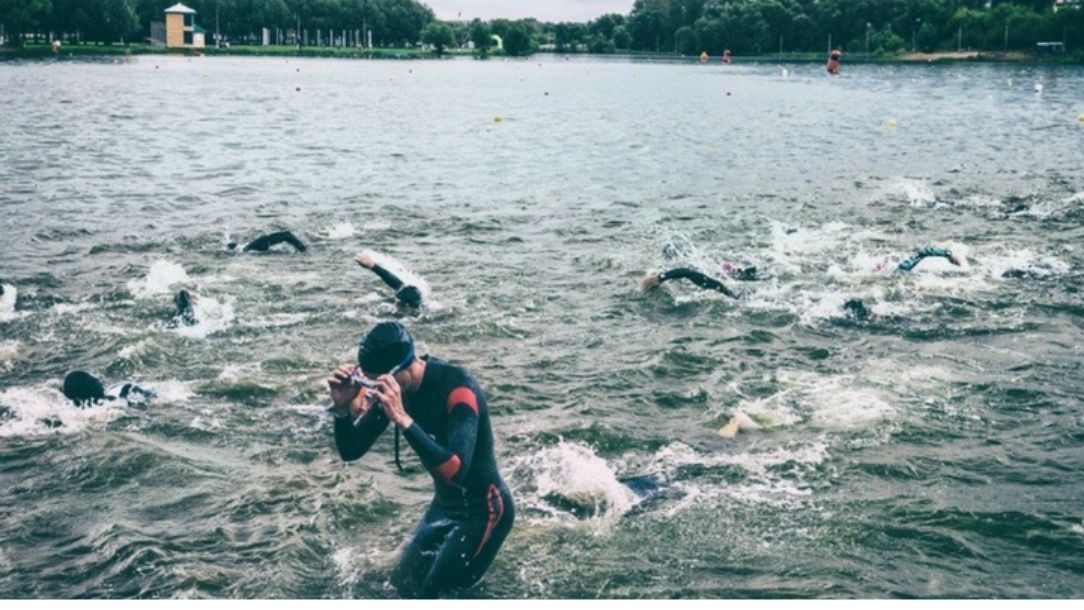 Several people swimming in open water, surrounded by a forest from a British Red Cross blog about drowning.