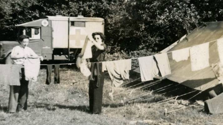 A black and white photograph showing women hanging up washing surrounded by tents in a field hospital.