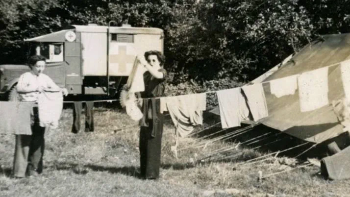 A black and white photograph showing women hanging up washing surrounded by tents in a field hospital.