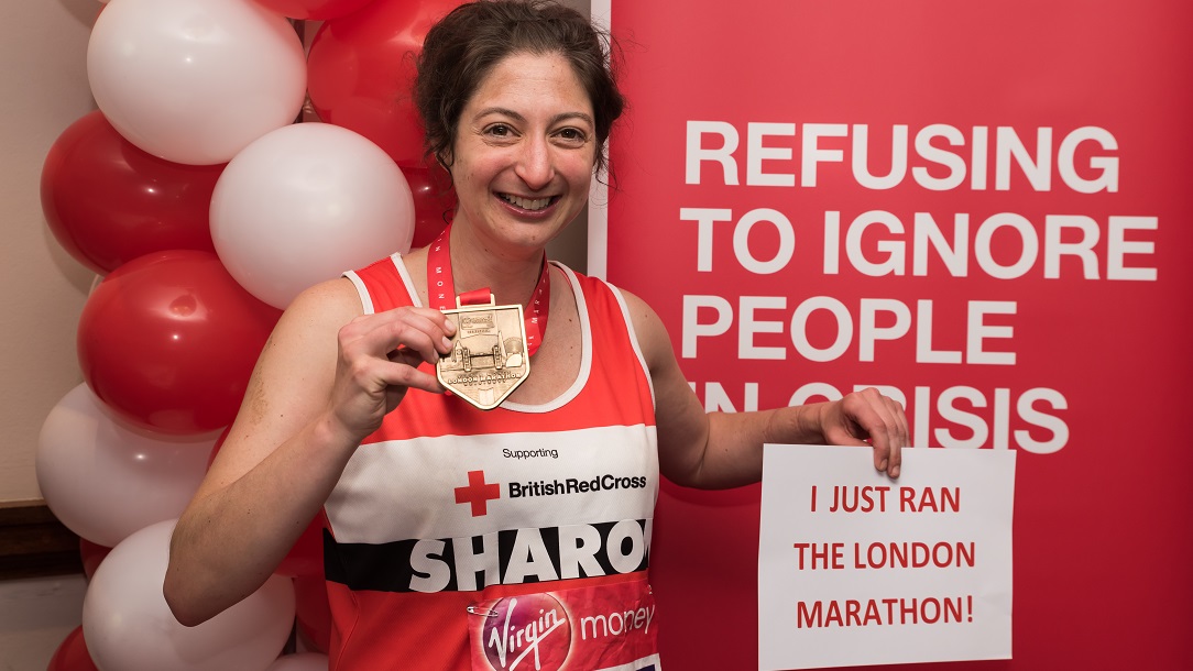 Lady holding up her medal after completing the London marathon.
