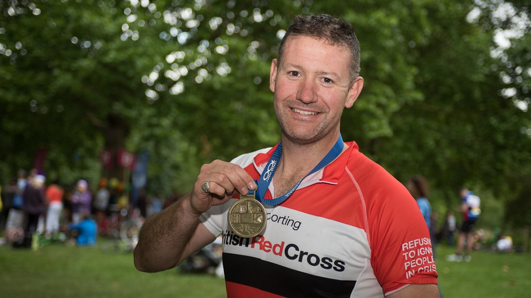 Man holding up his medal after completing the event.