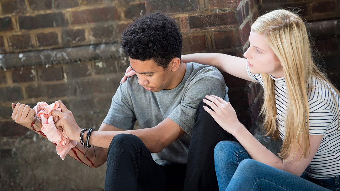 A girl comforts a boy while they wait for help to arrive.