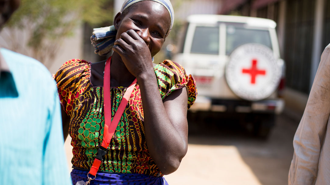 Smiling woman walks alongside Red Cross volunteers