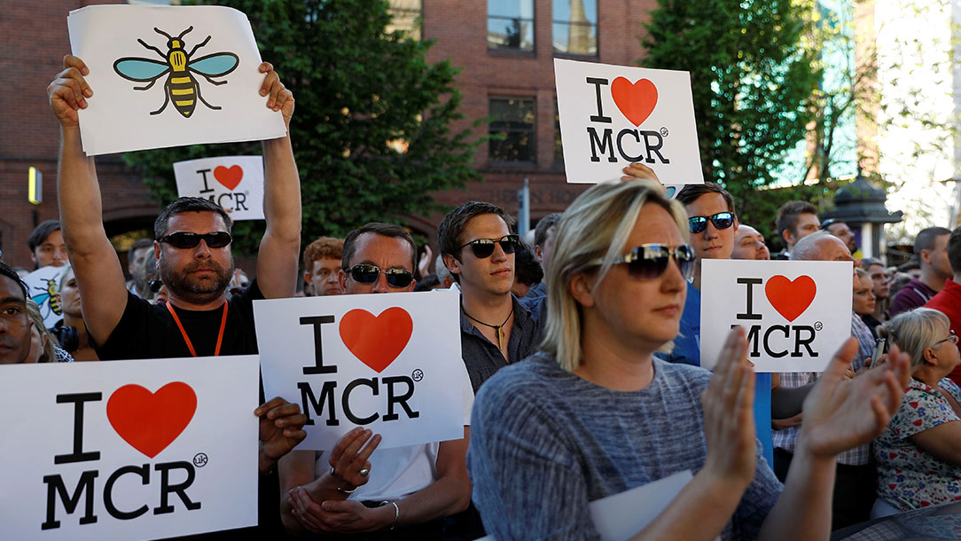 People hold placards as they take part in a vigil for the victims of an attack on concert-goers at Manchester Arena on 23 May 2017.