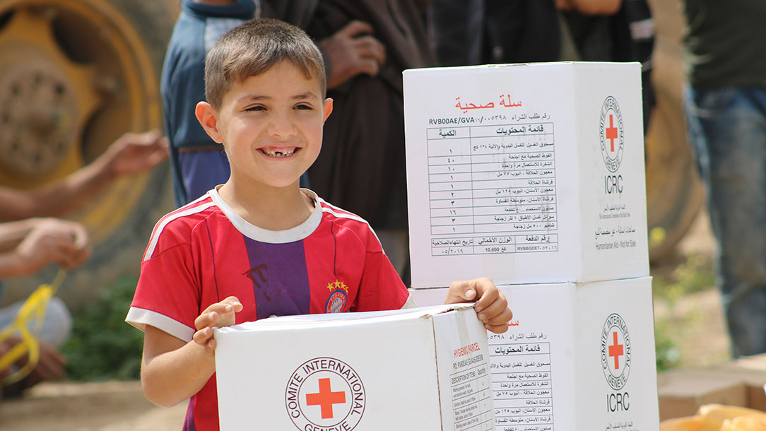 Child smiling by aid boxes